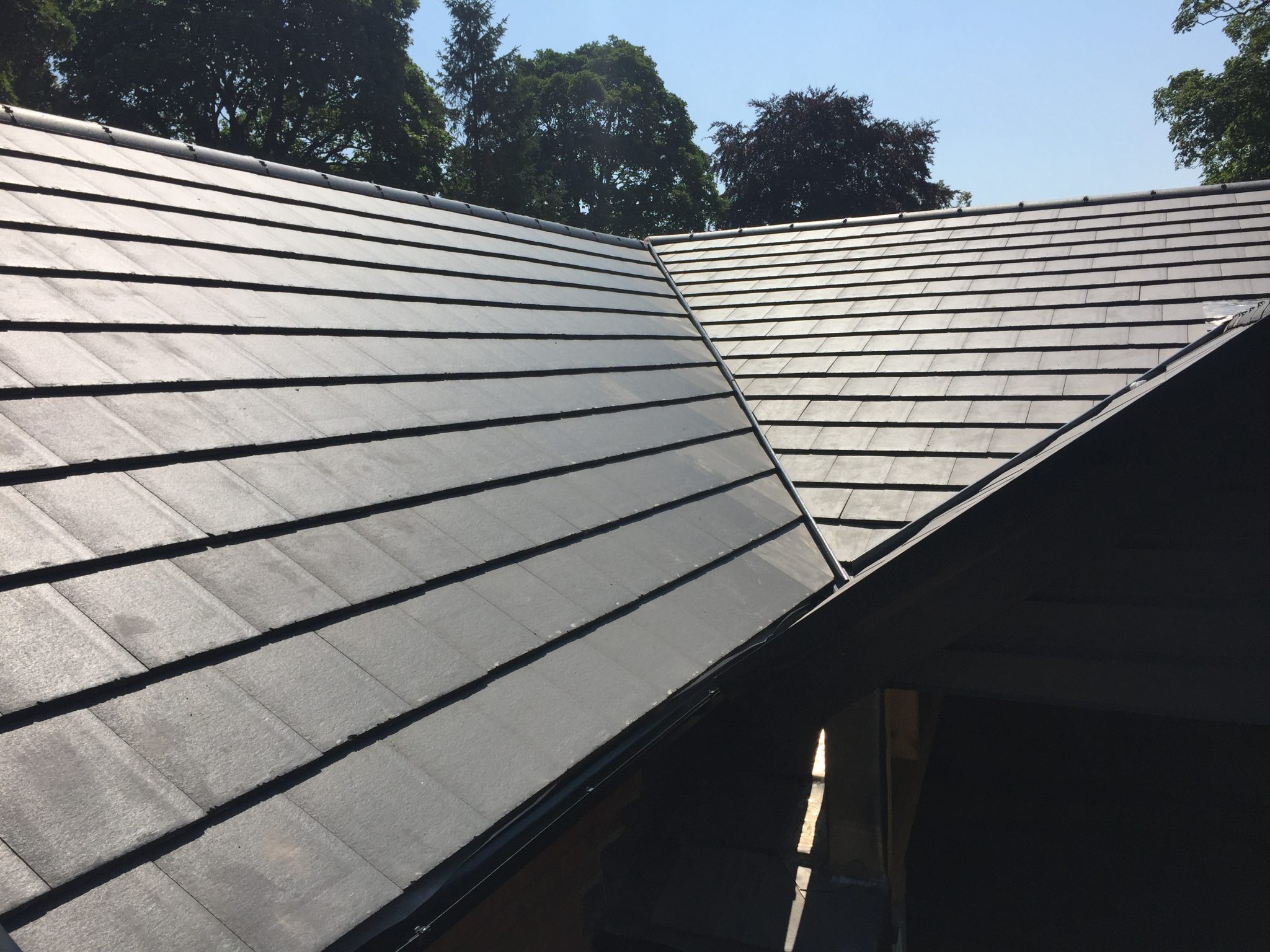 Newly completed dark grey tiled roof with a valley