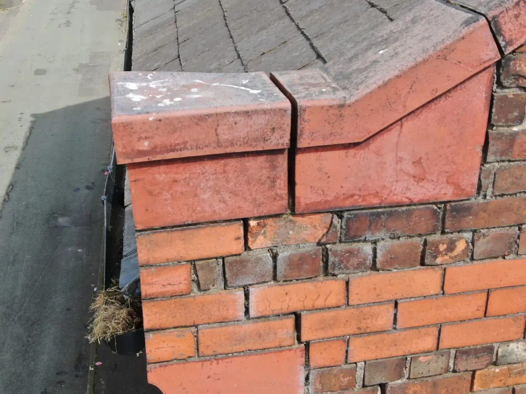 Brickwork: Brick chimney stack with weathered mortar joints and lead flashing where it meets the roof